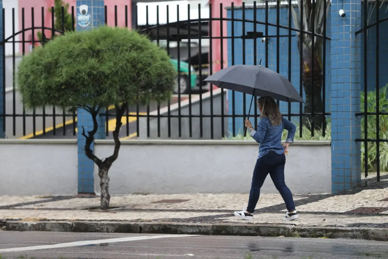 Pessoa com guarda-chuva caminha na rua durante precipitação em Fortaleza.