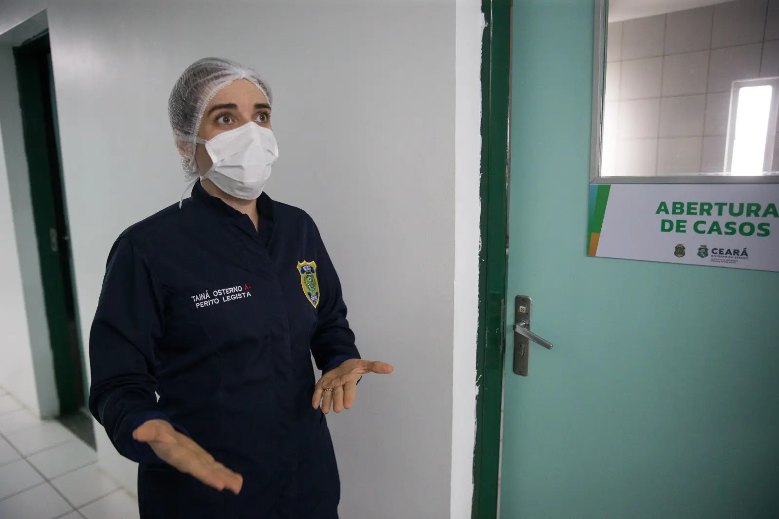 Perícia da Perícia Forense do Estado do Ceará falando na frente da porta do setor abertura de casos forenses.
