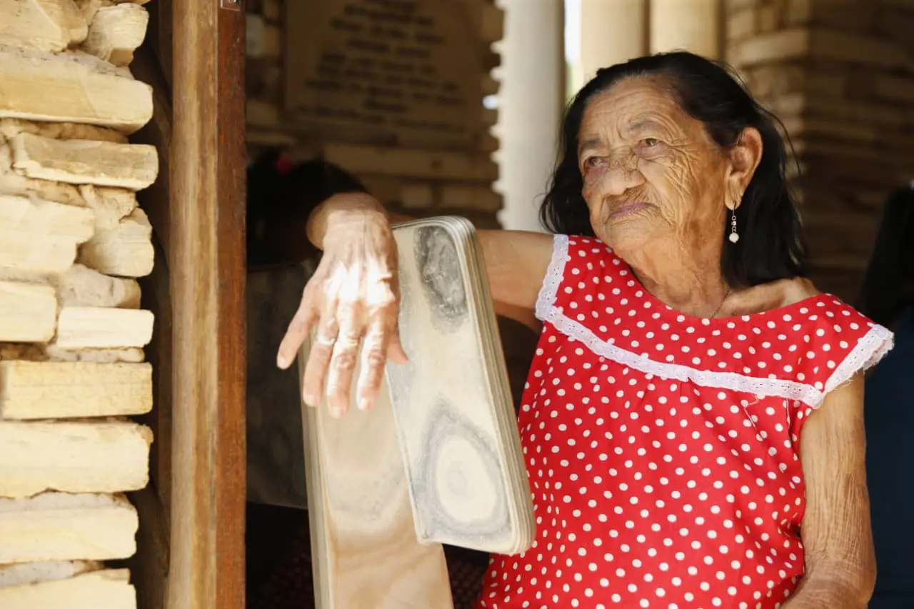 Idosa com blusa vermelha de bolinha em ambiente de casa de campo