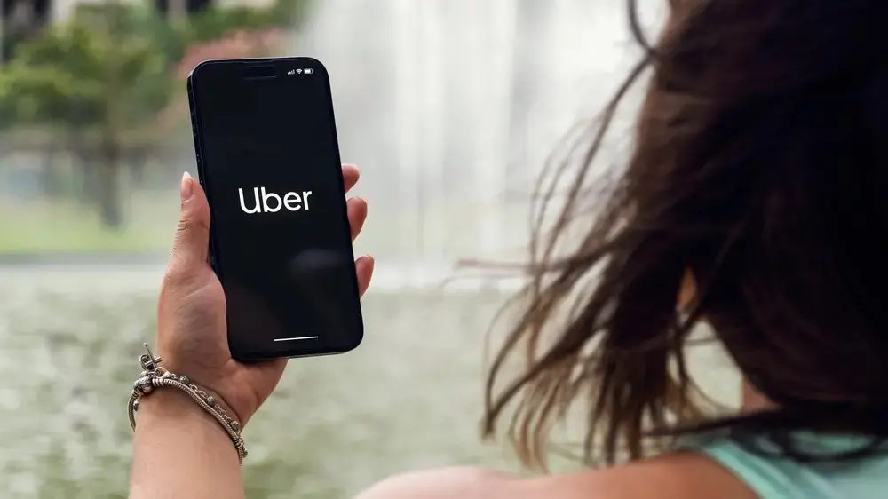 Mulher segura um celular de frente para ela. Na tela está escrito 