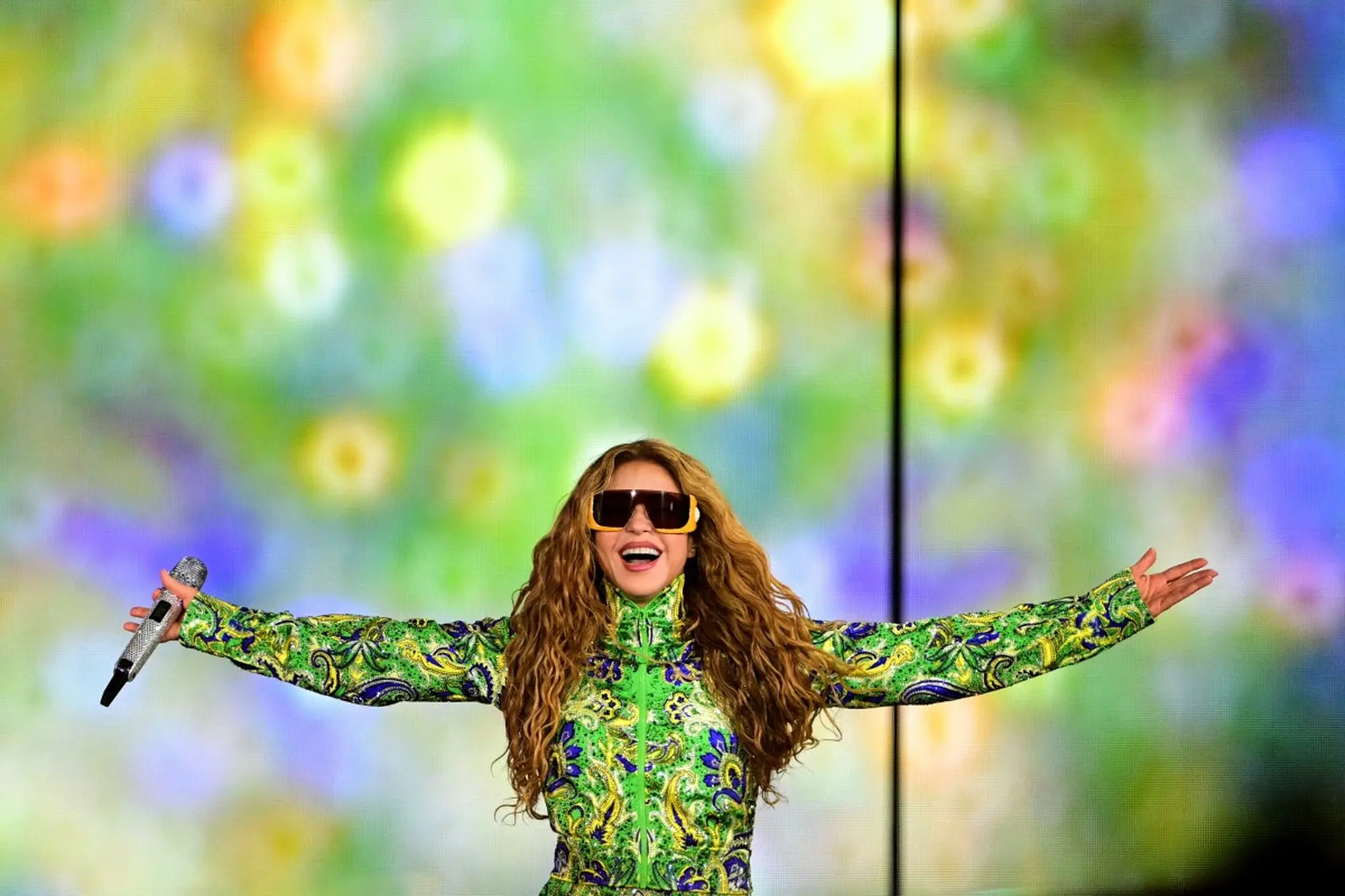 Shakira de braços abertos com figurino em homenagem às cores do Brasil.