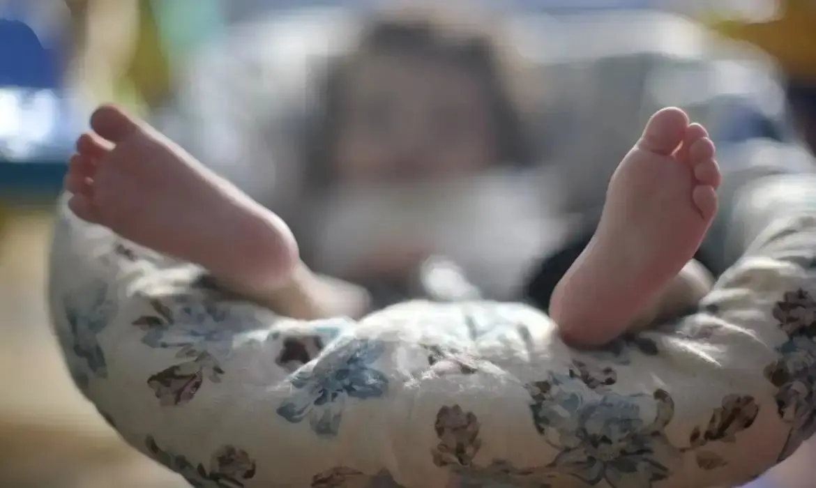 Dois pés de bebê recém-nascido em cima de almofada.
