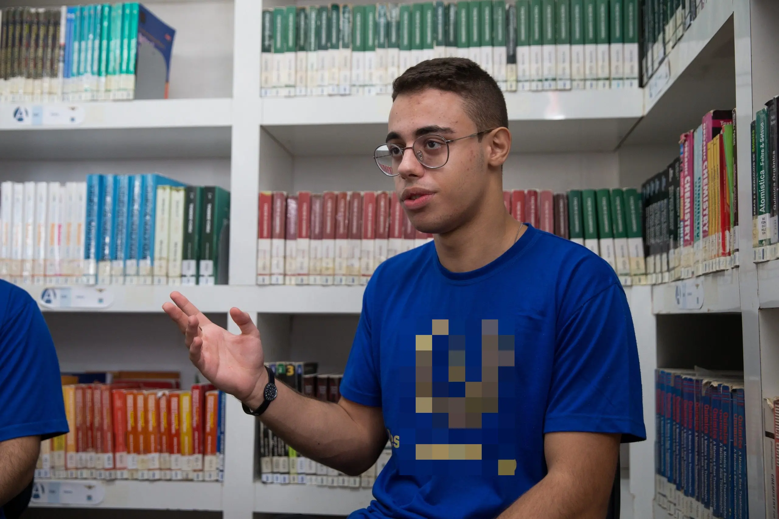 O jovem José Elias, de óculos e camiseta azul com o brasão dourado 