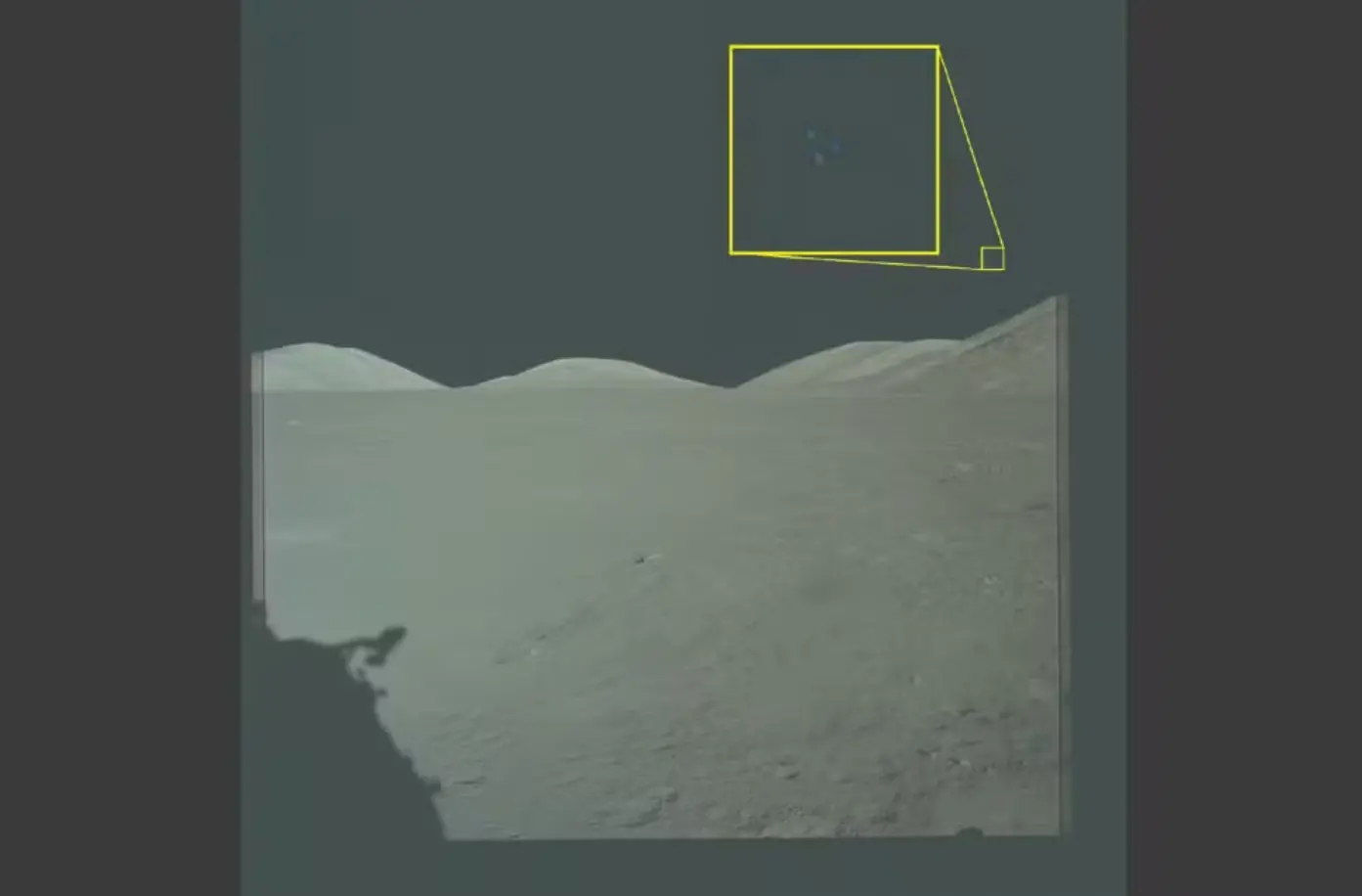 Área arenosa com ondulações, semelhante a dunas, sob fundo escuro. No canto superior direito, há formas geométricas delineadas em amarelo sobre a imagem.