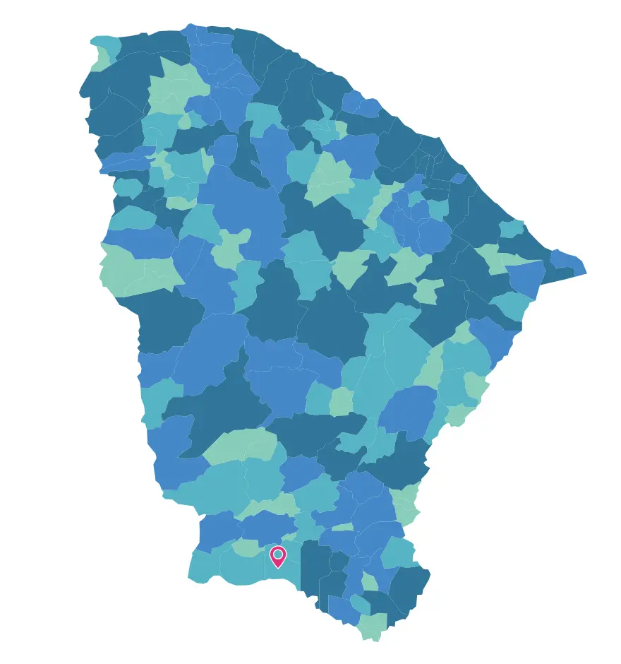 Na imagem, mapa político do estado do Ceará, dividido por municípios em diferentes tons de azul e verde sobre um fundo branco. Na região sul do estado, um ícone de localização (pin) na cor rosa com um círculo branco no centro marca a posição geográfica do município de Santana do Cariri.