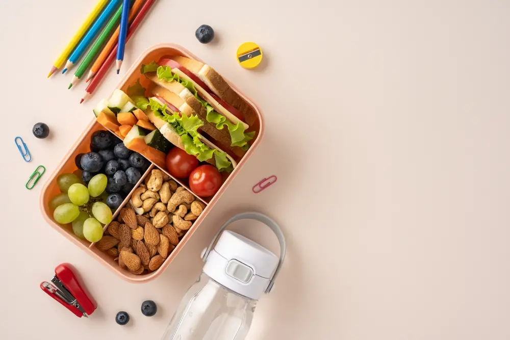 foto de lancheira escolar com saduíche, frutas e grãos.