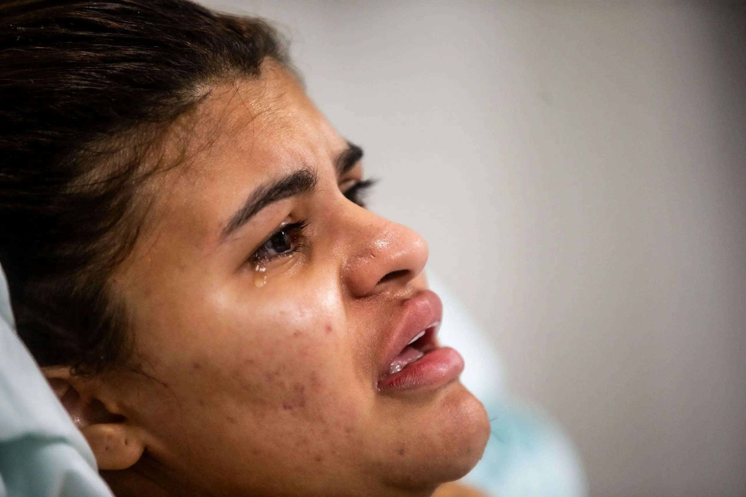 Foto de Ana Clara Oliveira chorando, jovem que teve as mãos decepadas a mando do ex-namorado no Ceará, deitada em cama de hospital.