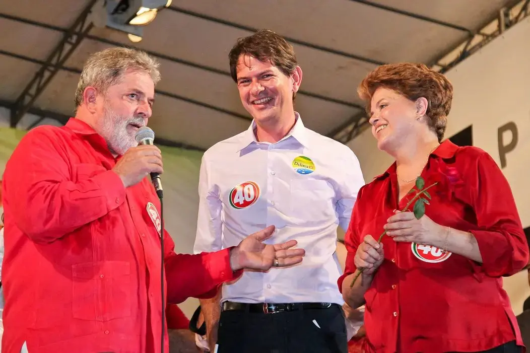 Lula fala ao microfone em palanque ao lado de Cid Gomes e Dilma Rousseff durante evento de campanha eleitoral do PT.