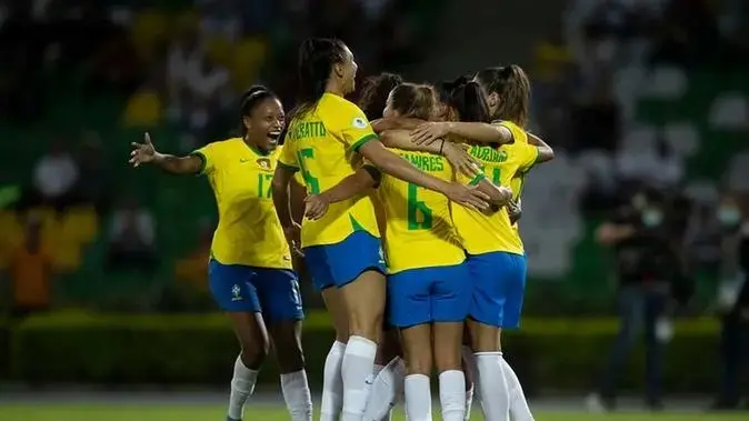 Imagem mostra jogadoras de futebol em abraço.