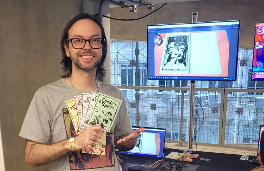 Renan Rodrigues, CEO da Supernova Games, com exemplares de um cordel inspirado no jogo em uma feira de jogos independentes.