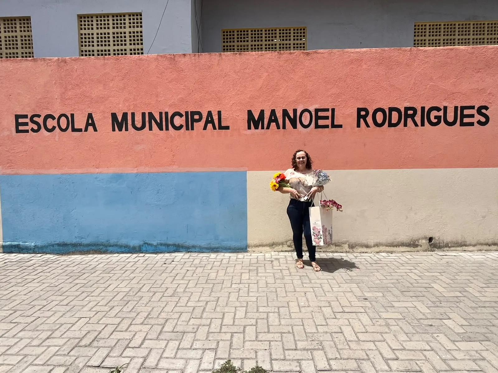 A professora na fachada da escola onde lecionou na última fase da carreira.