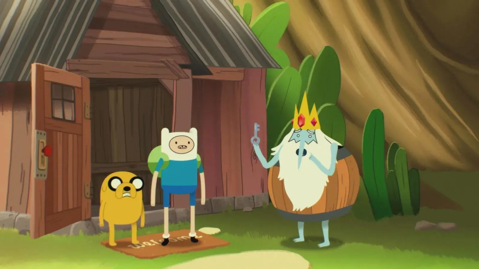 Finn, Jake e o Rei Gelado estão em frente a uma cabana de madeira cercada por vegetação. Finn e Jake aparecem na entrada da casa, enquanto o Rei Gelado, usando coroa e segurando uma chave, está posicionado ao lado.